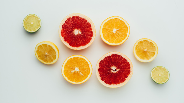 top view of fresh grapefruit, lemon, lime and orange slices, on grey - 写真・画像