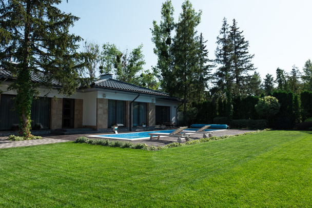 outside view of modern house, green lawn and poolside with sunbeds  - Fotografie, Obrázek