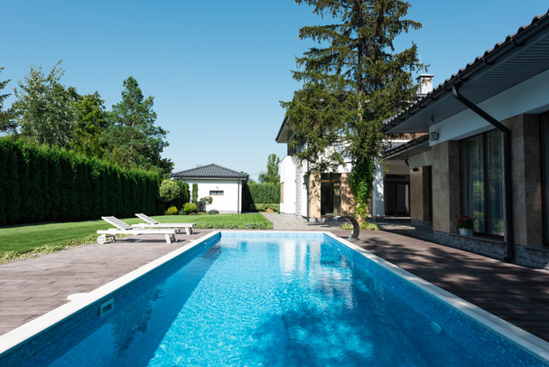 vue sur maison, jardin et piscine avec chaises longues pour se détendre
 - Photo, image