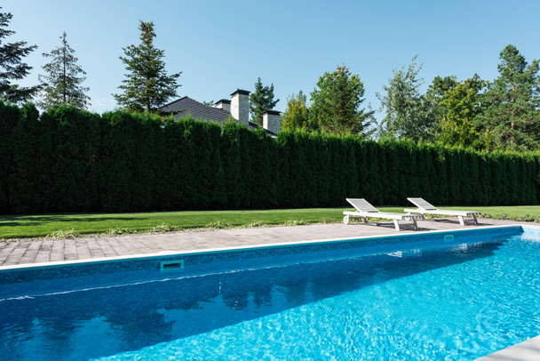 pohled na bazén s lehátky a zelený plot - Fotografie, Obrázek