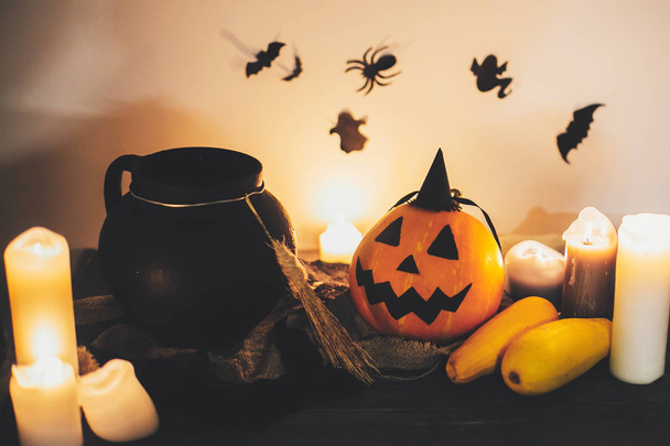 Happy Halloween. Jack o lantern pumpkin with candles, bowl, witch broom and bats, ghosts on background in dark spooky room. fall halloween image. spooky atmospheric moment - Photo, Image