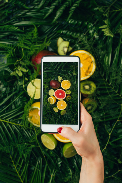 cropped view of food blogger taking photo of fresh fruits on smartphone - Photo, Image