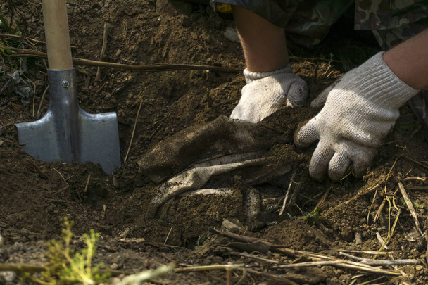 mani di un uomo in guanti bianchi rimuovere da terra un certo materiale scavato pacchetto
 - Foto, immagini