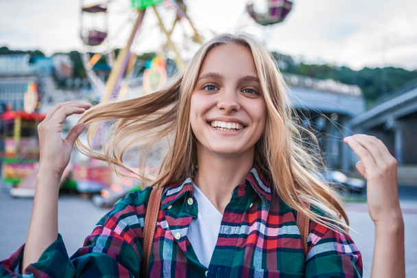 happy blonde girl smiling at camera while spending time in amusement park - Fotó, kép