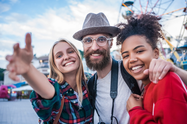 fröhliche junge multiethnische Freunde lächeln im Freizeitpark in die Kamera - Foto, Bild