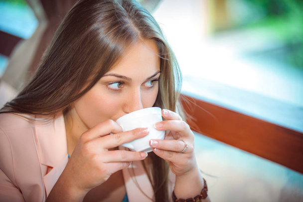 Young beautiful woman drinking coffee sitting at table in cafe - Φωτογραφία, εικόνα