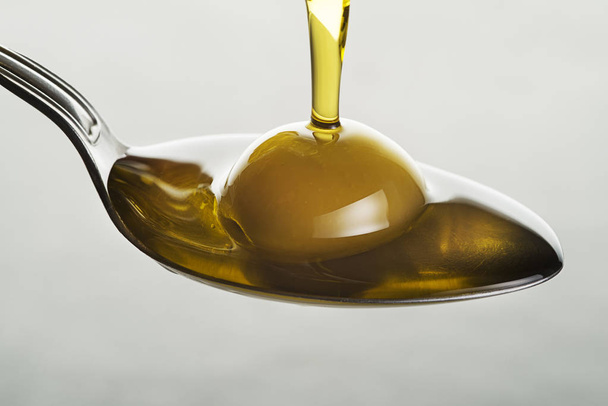 Bottle of virgin olive oil pouring to the spoon close up - Photo, image