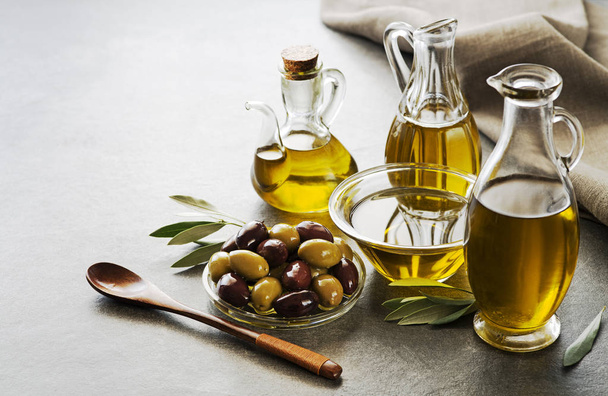 Bottles of Extra virgin healthy Olive oil with fresh olives on gray background - Photo, image