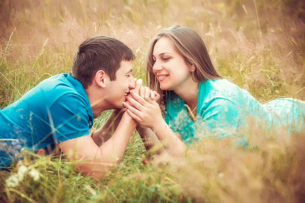 Romantic couple relaxing in field holding hands - Фото, изображение