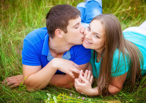 Romantic couple having fun and kissing relaxing in field - Фото, изображение