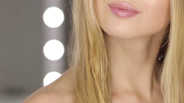 Junge Frau mit langen blonden Haaren steht vor dem Spiegel und blickt in die Kamera auf Spiegelhintergrund - Filmmaterial, Video