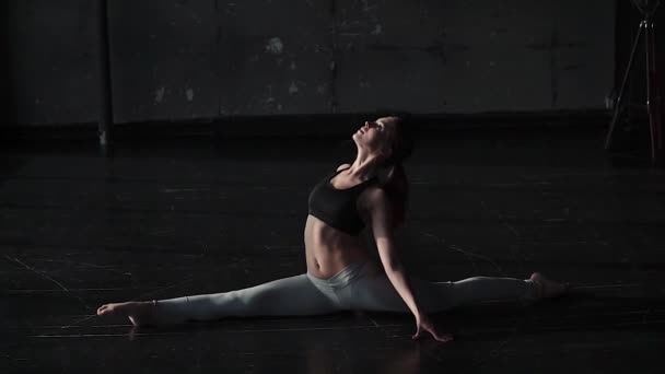 elastyczne i plastikowe dziewczyna praktykowania jogi samodzielnie w przestronnej sali ciemny. zwolnionym tempie - Materiał filmowy, wideo