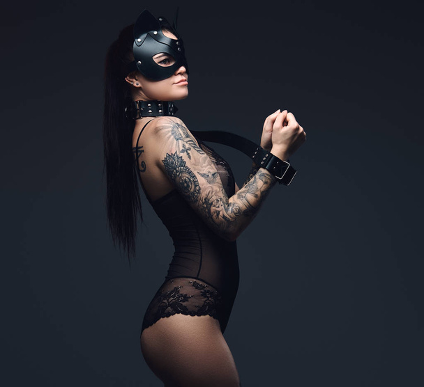 Sexy mujer con lencería negra en BDSM gato máscara de cuero y accesorios posando sobre fondo oscuro
.  - Foto, imagen