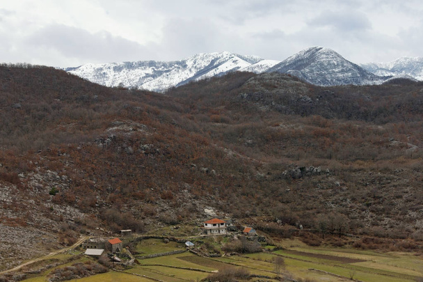 Paisagem de montanha com pequena aldeia no dia de inverno nublado. Montenegro, Alpes Dináricos, região de Sitnica
 - Foto, Imagem