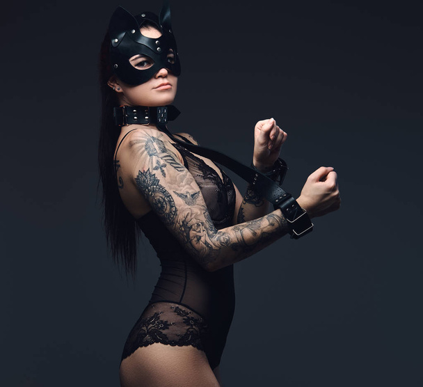 Sexy žena na sobě černé spodní prádlo v Bdsm maska kůže a příslušenství představuje na tmavém pozadí.  - Fotografie, Obrázek