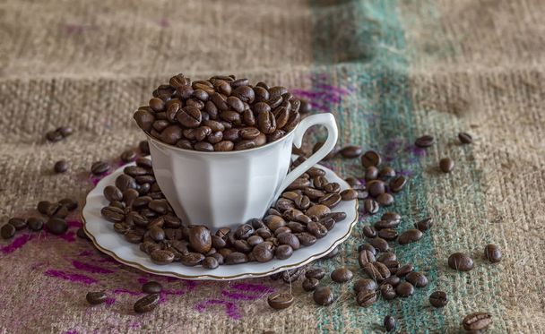 A cup of coffee full of coffee beans on a tat - Photo, Image