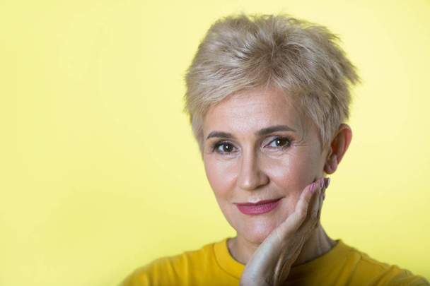 stylish elderly woman with a short hairstyle on a yellow background - Foto, afbeelding