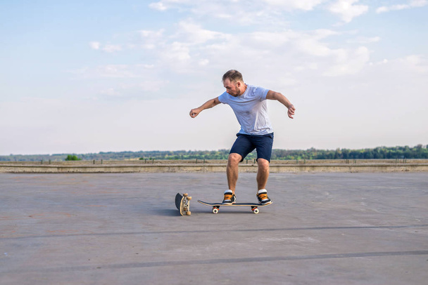 Young skateboarder performing a flip trick in a jump on the road, the free space. The concept of an active way of life. - Фото, зображення