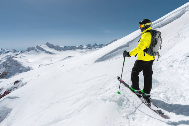 Portrait of a professional freerider skier standing on a snowy slope against the background of snow-capped mountains. The concept of winter sports - Photo, Image