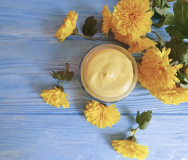 crema cosmética flores de crisantemo amarillo sobre un fondo azul
 - Foto, Imagen