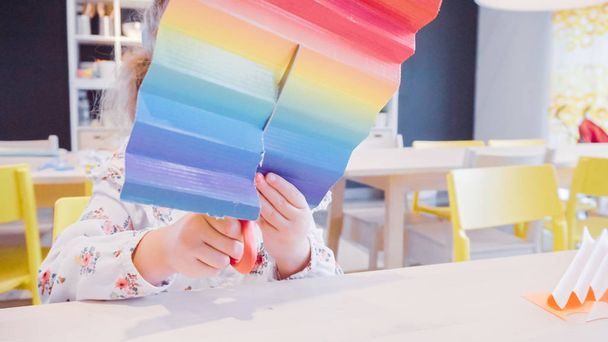 Κοριτσάκι που κάνει πεταλούδες χαρτί από πολύχρωμη χαρτί. - Φωτογραφία, εικόνα