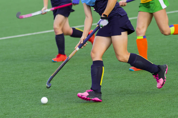 three women battle for control of ball during field hockey game - Photo, Image