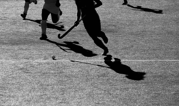 Silhouette. The shadow of a hockey players is running with a hockey stick on a hockey field. - Photo, Image