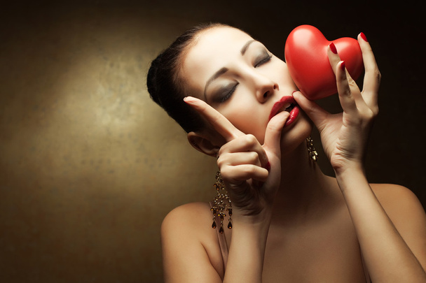 Portrait of a fashionable model with sexy red lips holding red h - Foto, imagen