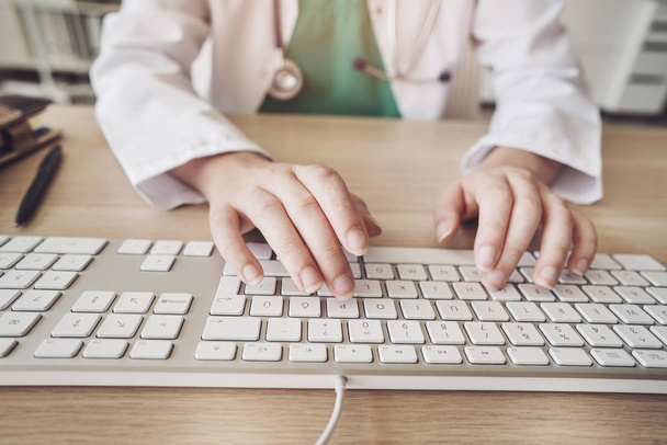 Tietokonetta käyttävä naispuolinen terveydenhuollon työntekijä
 - Valokuva, kuva