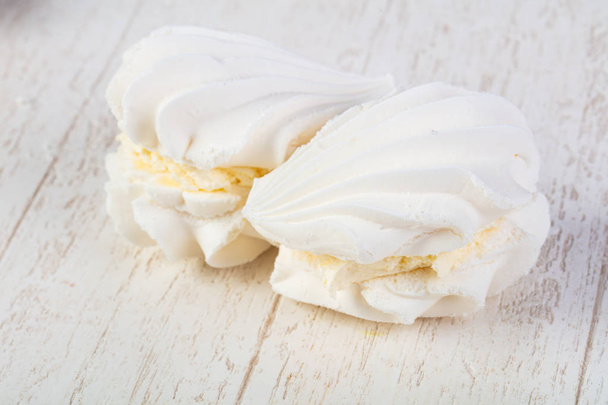 Dulce sabroso merengue ower fondo de madera
 - Foto, Imagen