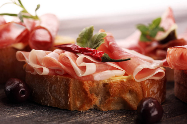 Sandwich con jamón o salami o crudo. Snack antipasti gourmet bruschetta
 - Foto, imagen