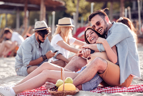 Boldog ifjú pár élvezi piknik a tengerparton, és jó szórakozást a nyári vakáció. - Fotó, kép