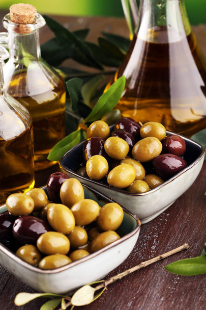 Bottle virgin olive oil and oil in a bowl with some olives. - Foto, imagen