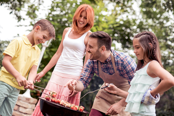 Food,people and family concept-man cooking meat on barbecue grill at summer garden party. - Photo, Image