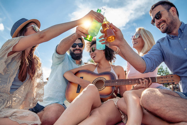 Cheerful friends with guitar enjoying weekend and having fun on the beach. - Foto, immagini