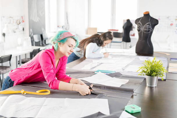 Широкий кут портрет сучасної молоді жінки працюють на кравці таблиці спільна робота із творчим мода дизайн-проект з азіатських колегою в сучасних atelier студії - Фото, зображення