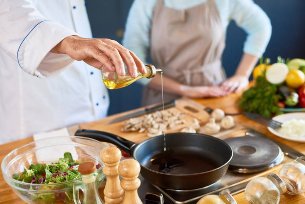 Close-up of male chef pouring oil into the pan - Photo, Image