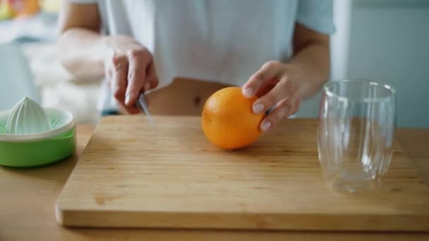 Cutting orange fruit for squeezing fresh juice. Close up female hands - Footage, Video