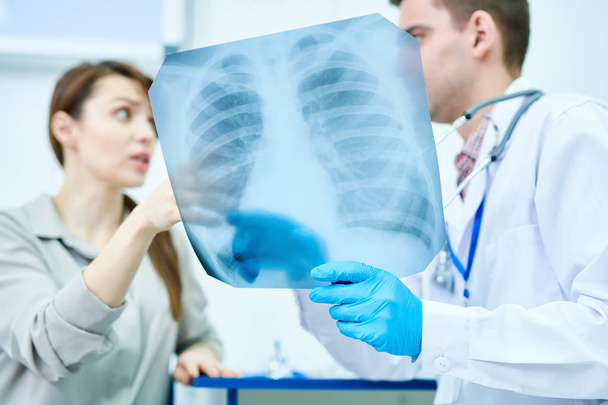 Retrato de cintura hacia arriba del médico que sostiene la radiografía de tórax explicando al paciente femenino, espacio para copiar
 - Foto, Imagen