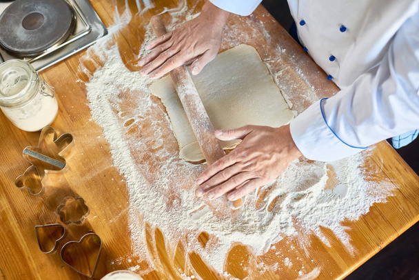 Крупный план шеф-повара выкатывает тесто на стол
 - Фото, изображение