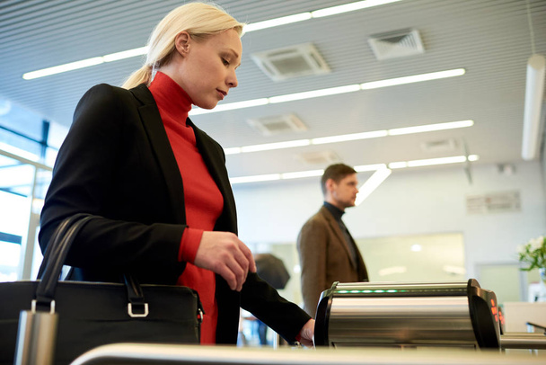 Side view portrait of pretty blonde businesswoman swiping card passing turnstile to enter building - Photo, Image
