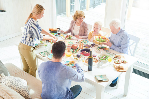 Boldog két generációs családi vacsorával együtt portréja ül ünnepi asztal ízletes ételeket ünnep ünnepe, napfény, közben másolja a hely - Fotó, kép