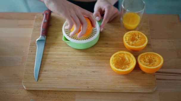 Manos de mujer haciendo jugo de naranja natural en tablero de madera
 - Imágenes, Vídeo
