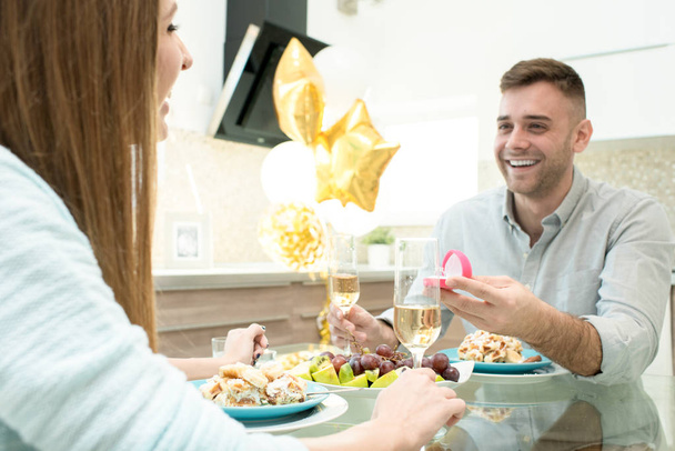 Gelukkig opgewonden knappe jonge man met romantisch diner aan tafel zit en huwelijksaanzoek aanbrengen geliefde vrouw geven sieraden ring aan haar - Foto, afbeelding