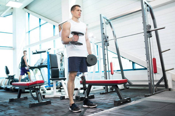 Teljes hossza protézis láb dolgoznak ki súlyokkal modern edzőteremben szép izmos férfi portréja - Fotó, kép