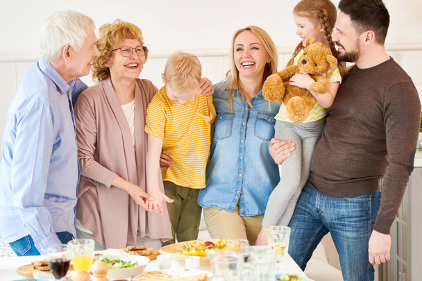 Portrait of carefree two generation family of six posing  at home and smiling happily while  standing at festive dinner table - Фото, зображення