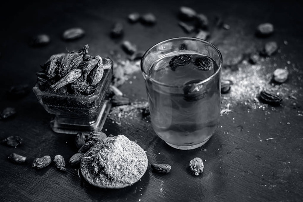 Close up of water of Black cardamom with its powder and raw whole black cardamom. - Foto, afbeelding