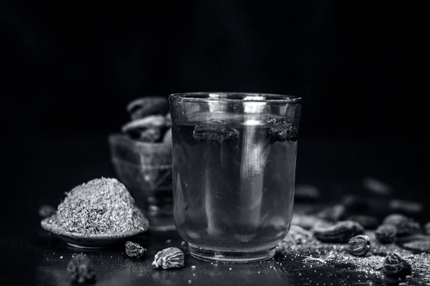 Close up of water of Black cardamom with its powder and raw whole black cardamom. - Fotó, kép