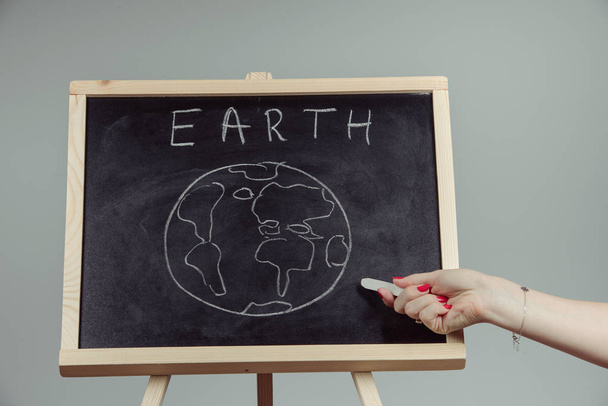 earth written on blackboard with earth symbol, background, high resolution, gray background - Zdjęcie, obraz