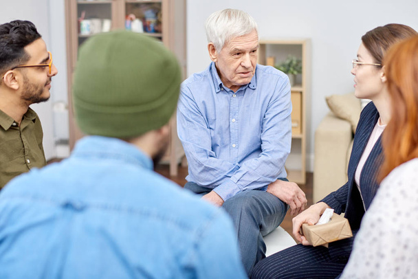 Support group of different age having psychological therapy: they sitting in circle and sharing their problems with highly professional psychologist and other patients - Foto, Imagem